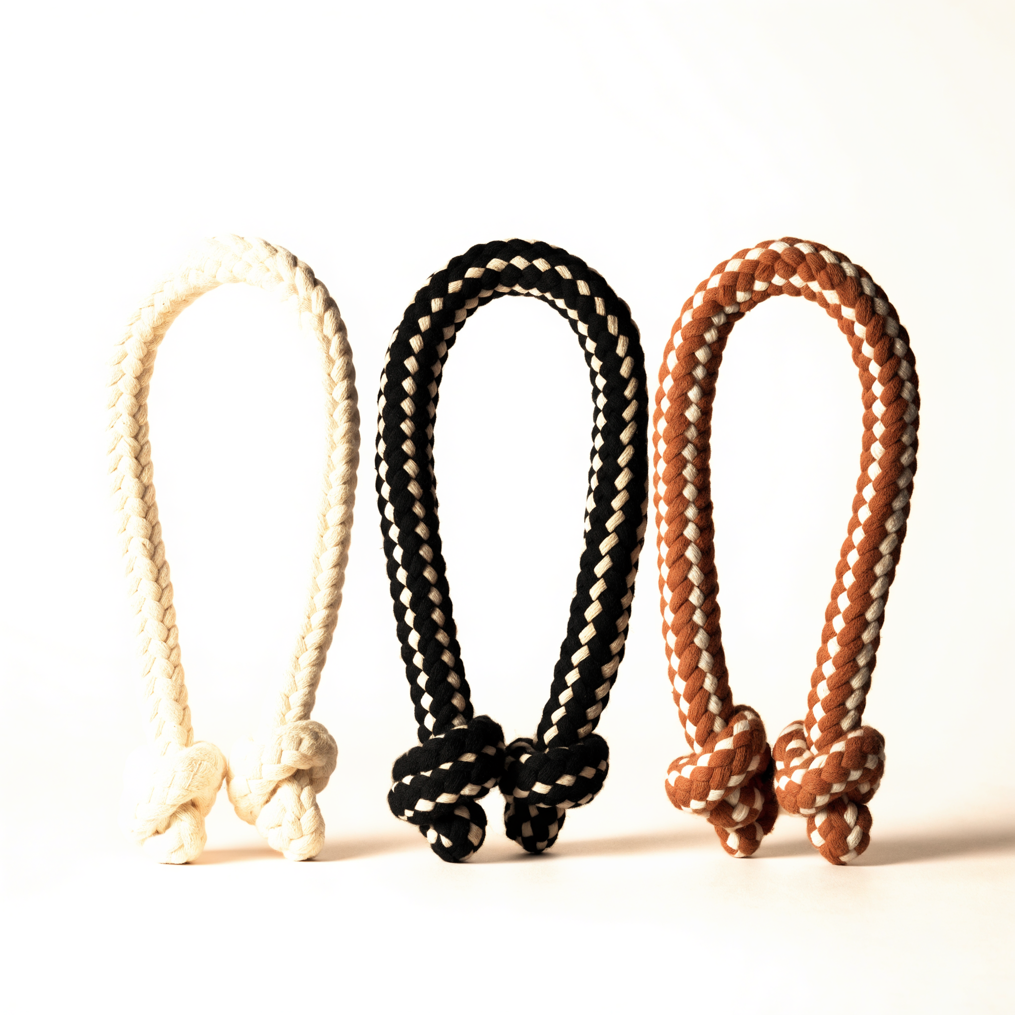Set of three braided cotton rope dog toys in natural, ink and terracotta